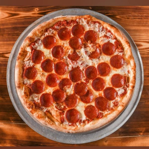 Genova's Italian Restaurant pepperoni pizza on a metal tray, on a rustic wooden table.